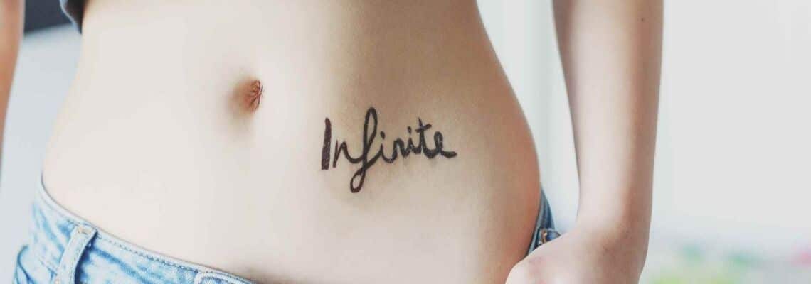 Scarred lettering tattoo on the stomach